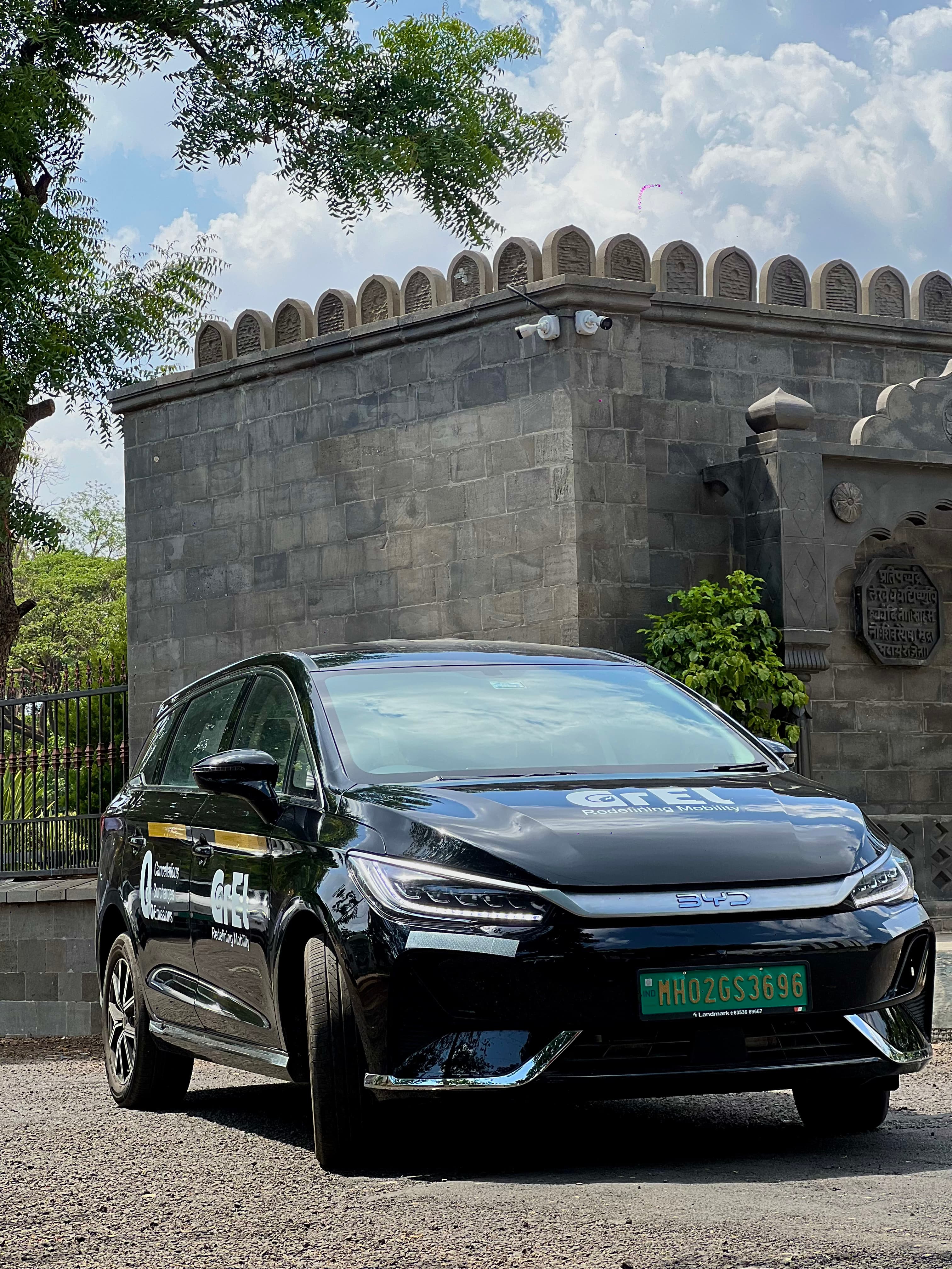 A black GrEL BYD eMAX 7 parked in front of a stone fort wall
